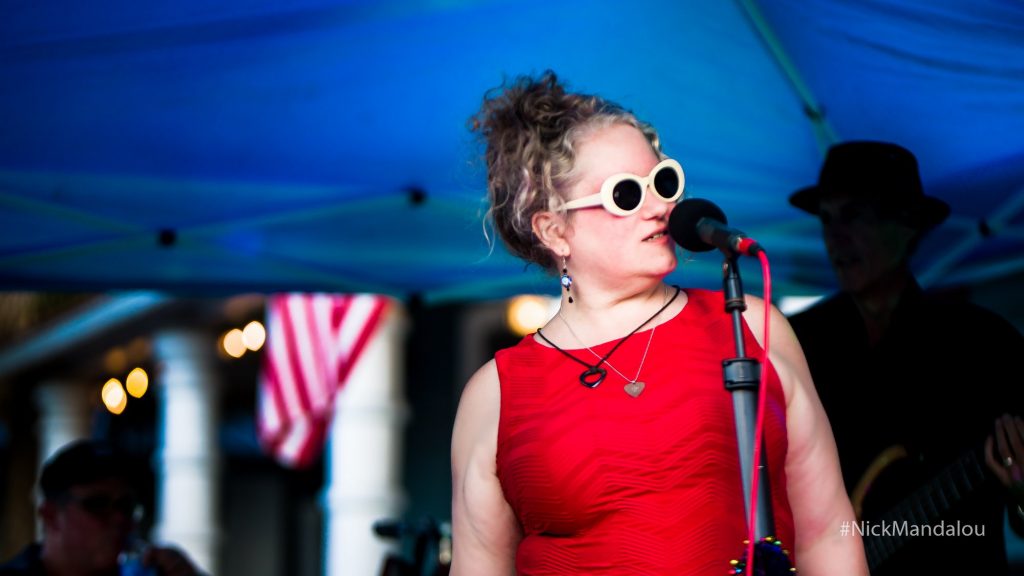 Julie Black in red dress at microphone